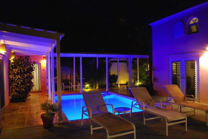 At night, the pool lights changing colors gently illuminate the courtyard